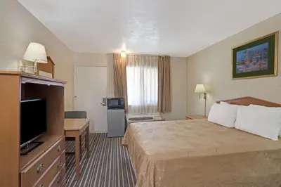 a hotel room with a bed and a flat screen tv at Buena Park Inn in Anaheim