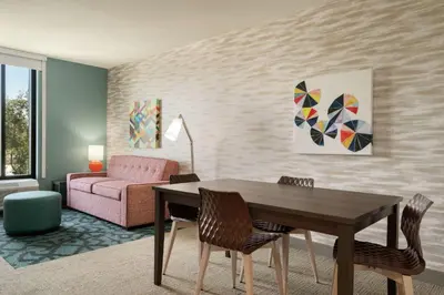 a living room with a table and a pink couch at Home2 Suites By Hilton Woodland Hills Los Angeles in Woodland Hills