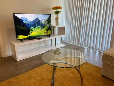 a living room with a tv and a glass table at ViewPoint Suites in Los Angeles
