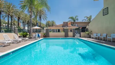 a swimming pool with chairs and a house and palm trees at Anaheim Islander Inn and suites near Park and Convention center in Anaheim