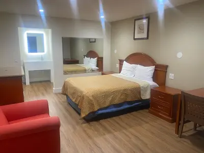 a hotel room with two beds and a red chair at Royale Inn Motel in Whittier