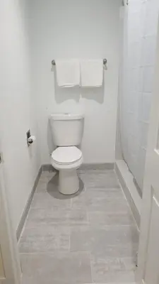 a white bathroom with a toilet and towels at Royale Inn Motel in Whittier