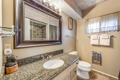 a bathroom with a sink and a toilet and a mirror at Adorable Explorable in Lake Arrowhead
