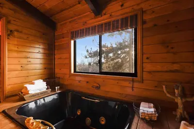 a bathroom with a sink and a window in a log cabin at Howard's Cabin in Lake Arrowhead