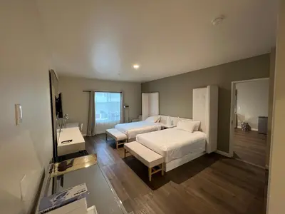 a bedroom with two beds and a television in it at ASPIRE INN & SUITES Orange in Orange