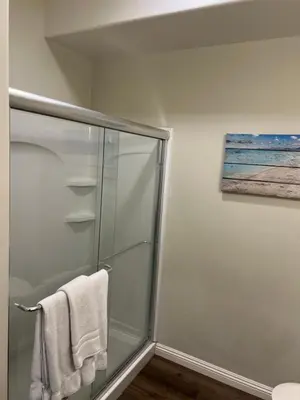 a bathroom with a shower with a glass shower stall at ASPIRE INN & SUITES Orange in Orange