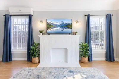 a living room with a white fireplace and blue curtains at Modern LA Home Near Museums, Dining & Downtown in Los Angeles