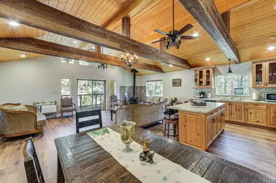 an open kitchen and living room with wooden ceilings at Cozy Pine Mountain Club Cabin with Large Deck in Pine Mountain Club