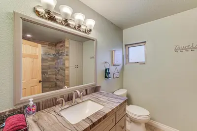a bathroom with a sink and a toilet and a mirror at Cozy Pine Mountain Club Cabin with Large Deck in Pine Mountain Club