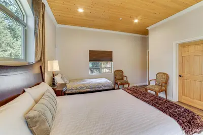 a bedroom with a bed and two chairs and a window at Cozy Pine Mountain Club Cabin with Large Deck in Pine Mountain Club