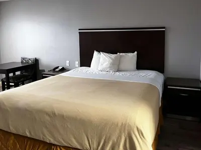 a bedroom with a large white bed with a desk at Studio 6 Artesia CA in Artesia