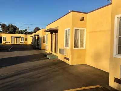 an empty parking lot next to a yellow building at Deluxe Inn in Pomona