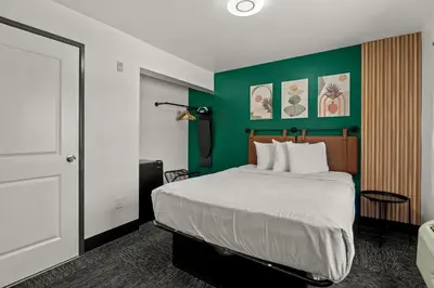 a bedroom with a bed and a green wall at Hollywood Le Bon Hotel in Los Angeles