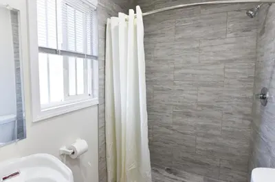 a bathroom with a shower curtain and a sink at Holly Park Motel near LAX in Inglewood