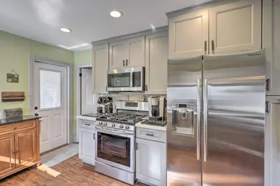 a kitchen with white cabinets and stainless steel appliances at Charming Craftsman Bungalow with Garden and Hot Tub! in Fullerton