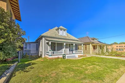 a yellow house with a porch and a yard at Riverside House with Yard about 1 Mi to Downtown! in Riverside