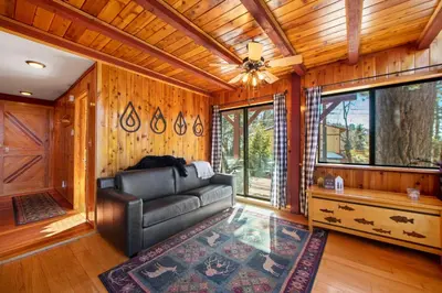 a living room with a leather couch and wooden walls at The Valley's Cabin in Green Valley Lake