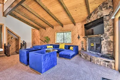 a living room with a blue couch and a fireplace at Luxe Escape with Decks, Mtn Views, Game Room! in Frazier Park