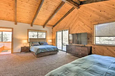 a bedroom with a bed and a flat screen tv at Luxe Escape with Decks, Mtn Views, Game Room! in Frazier Park