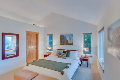 a white bedroom with a bed and windows at Beautiful Lake Arrowhead Cabin with EV Charger in Lake Arrowhead
