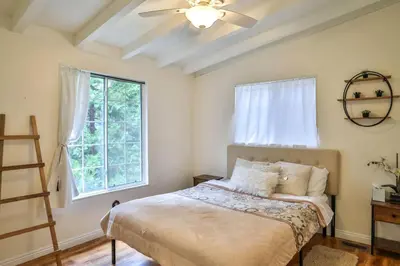 a bedroom with a bed with a ceiling fan and a window at Lake house Cabin - Lake Arrowhead in Lake Arrowhead
