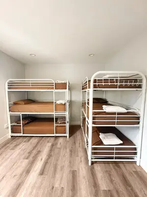 two white bunk beds in a room with wood floors at Fruit Hostel in Los Angeles