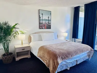 a bedroom with a bed with two lamps and a plant at Foghorn Harbor Inn in Los Angeles