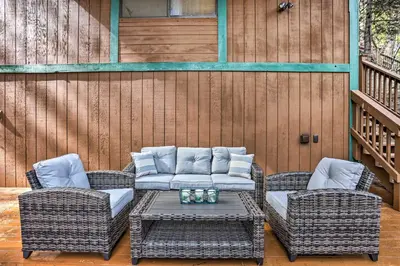 a patio with wicker chairs and a table with a couch at Woodsy Twin Peaks Getaway with Hot Tub and Views! in Twin Peaks