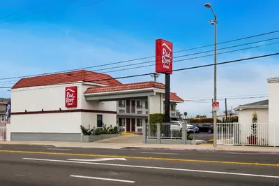a building with a red sign on the side of a street at Red Roof Inn Carson - Wilmington, CA in Wilmington