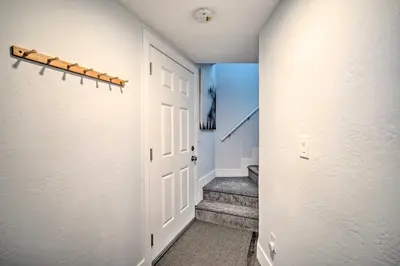 a hallway with a white door and stairs at Chic Running Springs Forest Cabin with Deck! in Running Springs