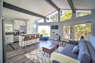 a living room with a blue couch and a kitchen at Chic Running Springs Forest Cabin with Deck! in Running Springs