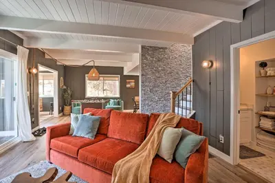 a living room with a red couch and a stone wall at Stunning Lake Arrowhead Cabin with Lake Views! in Lake Arrowhead