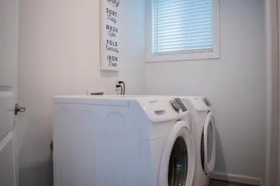 a white washing machine in a bathroom with a window at Luxury Beachfront Condo - Endless Views - Surf 1 in Sunset Beach