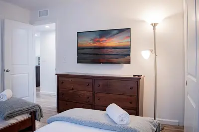 a bedroom with a bed and a dresser and a lamp at Luxury Beachfront Condo - Endless Views - Surf 1 in Sunset Beach