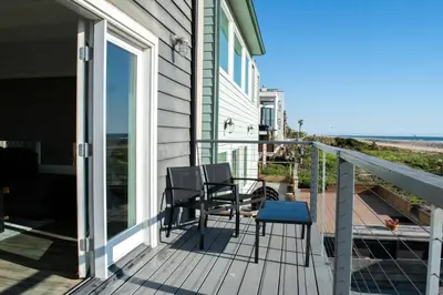 a porch with two chairs and a table on it at Luxury Beachfront Condo - Endless Views - Surf 1 in Sunset Beach