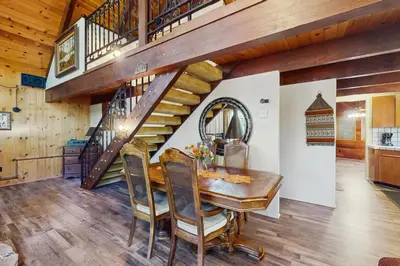 a dining room with a wooden table and a staircase at Retro Cabin in Lake Arrowhead