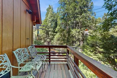 a deck with two chairs and a man standing on it at Retro Cabin in Lake Arrowhead