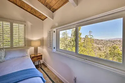 a bedroom with a bed and a large window at Ridgeline Retreat with Mountain Lake Views! in Lake Arrowhead