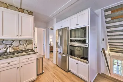 a kitchen with white cabinets and stainless steel appliances at Ridgeline Retreat with Mountain Lake Views! in Lake Arrowhead