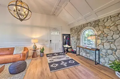 a living room with a couch and a stone wall at Ridgeline Retreat with Mountain Lake Views! in Lake Arrowhead
