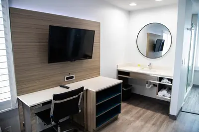 a room with a desk and a tv on a wall at Pico Rivera Inn and Suites in Pico Rivera