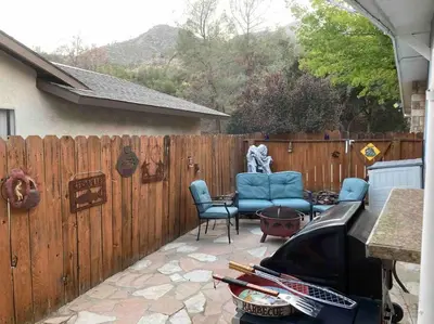 a patio with blue chairs and a fence at Kernville - walk to River Kern & Downtown in Kernville