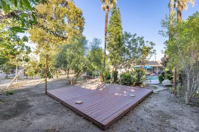 a wooden deck in the middle of a yard with trees at Spacious Home with Garden & Pool in Northridge