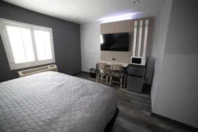a bedroom with a bed and a table and a television at Palms Motel in Pico Rivera