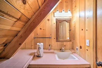 a bathroom with a sink and a mirror and wooden walls at Running Springs Cabin with Large Deck and View! in Running Springs