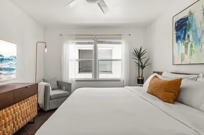 a white bedroom with a bed and a chair at Spacious Coastal Apartment in a Colorful Community - NRP22-00590 in Long Beach