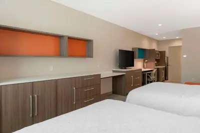 a hotel room with two beds and a desk and a kitchen at Home2 Suites By Hilton Redlands in Redlands