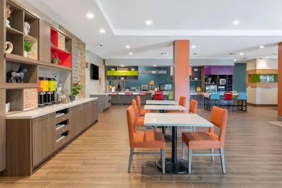 a cafeteria with a table and chairs and a kitchen at Home2 Suites By Hilton Redlands in Redlands