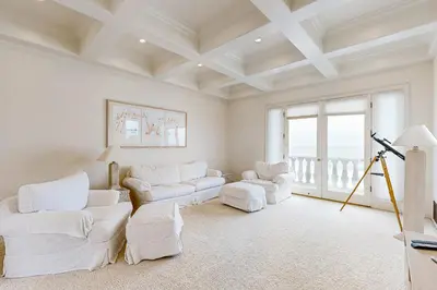 a living room with white furniture and a large window at Breakers Way Dream in Carpinteria