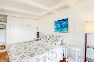a white bedroom with a bed and a painting on the wall at Sailaway Cabin B in Ventura